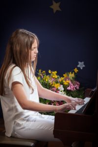 girl playing piano - music scholarships